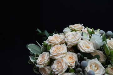 Obraz na płótnie Canvas Beautiful wedding bouquet of bushy cream rose, eucalyptus, Brunei, Pittosporum and Lisianthus on a black background.