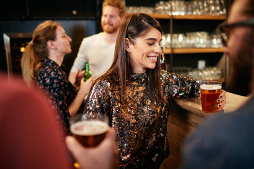 Group of friends drinking beer, chatting and having good time at pub. Night out.