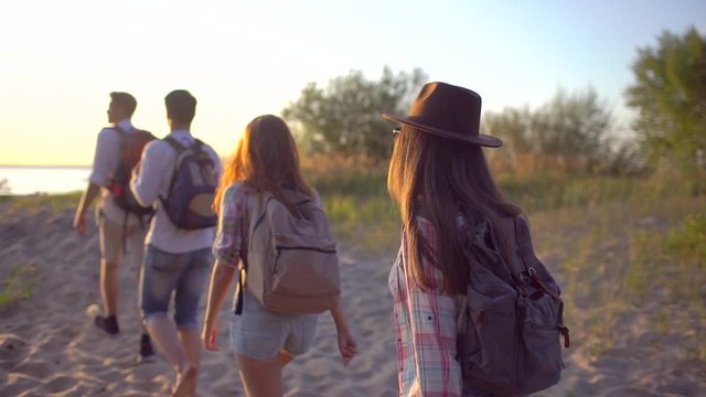 Group of young hikers tourists walking to beach nature mountains at sunset, Hipster friends woman man travelers hiking with backpack. summer trip vacation adventure travel tourizm landscape ocean slow