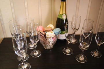 Bottel of champagne with glasses and macaroons on the table