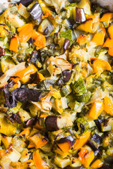 Vegetable ratatouille oven cooked  in a plate with cooking paper, over a white rusty table, bottle  and glass of wine defocused in the blue background.