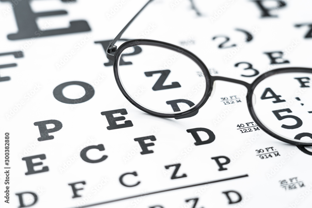 Wall mural Black glasses on the eye chart with concept of vision protection