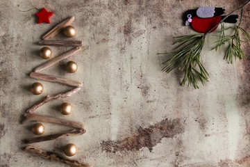 Christmas tree made of wooden branches and bullfinch on a pine branch