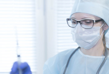 Medicine health background. Female doctor in mask and gloves holding a syringe with medicine, close-up