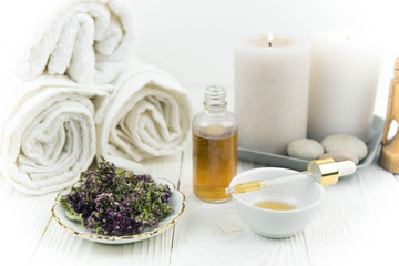 Fototapeta na wymiar Spa treatment bottle of natural organic oil essence serum collagen. Towel, aromatic candles, flowers, massage brush and Buddha on white background. Copy space for text. Beautiful woman hands. Oil drop