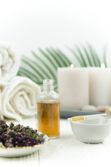 Spa treatment bottle of natural organic oil essence serum collagen. Towel, aromatic candles, flowers, massage brush and Buddha on white background. Copy space for text. Beautiful woman hands. Oil drop