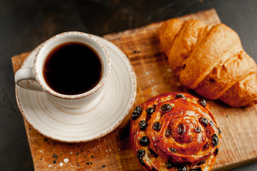 Coffee and croissant, bun on a stone table. morning breakfast