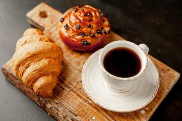 Coffee and croissant, bun on a stone table. morning breakfast