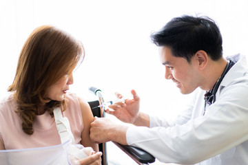 Doctor injecting vaccine to woman patient on her arm close up.