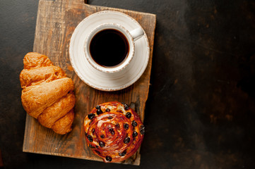 Coffee and croissant, bun on a stone table. morning breakfast, with copy space for text
