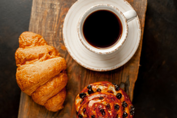 Coffee and croissant, bun on a stone table. morning breakfast