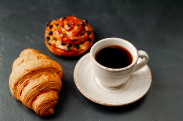 Coffee and croissant, bun on a stone table. morning breakfast