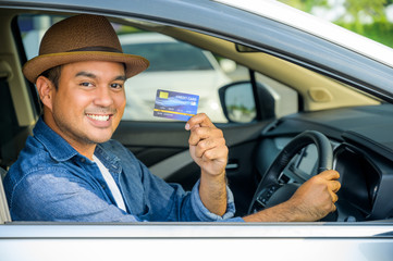 An Asian man is holding a credit card in his hand. While he was driving This picture is about...