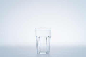 Mineral drinking water in a glass close up on white background with copy space.