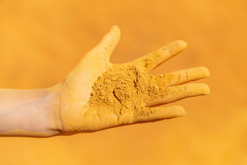 Open hand fingers spread dirty with yellow ochre powder dirt dust sand close up Roussillion, France...