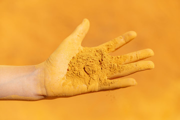 Open hand fingers spread dirty with yellow ochre powder dirt dust sand close up Roussillion, France in summer on holiday