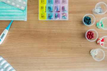 Capsule and pills medicines with thermometer, mask and pillbox in wood background close up