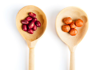 Peanuts and hazelnuts in wooden spoon, isolated on white