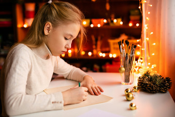 Small blonde child writes the letter to Santa