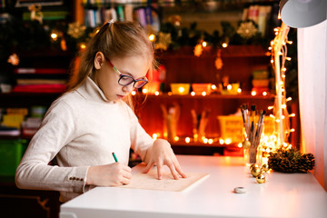 Small blonde child writes the letter to Santa