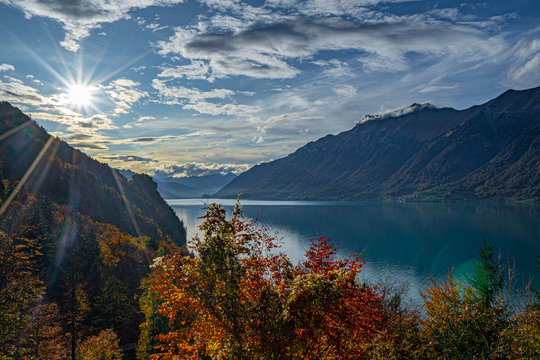 Brienzersee im Herbst vom Giessbach Grand Hotel tiefliegende Sonne Wolken blauer Himmel farbige B&auml;ume Abendstimmung