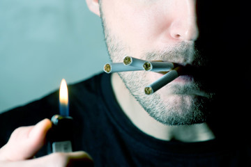 a man with a half-lit face looks skeptical and cigarettes stick out from his mouth, No eyes