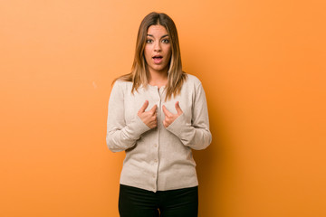 Young authentic charismatic real people woman against a wall surprised pointing with finger, smiling broadly.