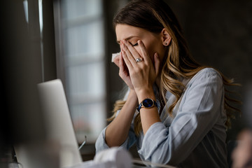 Young businesswoman having migraine while working late in the office.