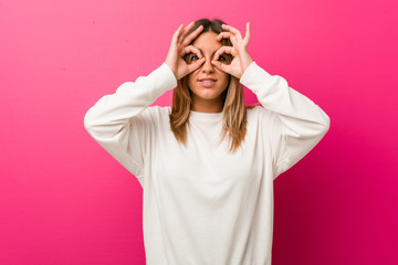 Young authentic charismatic real people woman against a wall showing okay sign over eyes