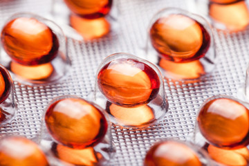 Metal drug blister with red orange medicine capsules. Vibrant color cure in transparent silver...