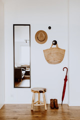 Minimal Scandinavian interior design concept. Living room with mirror, stool, hat, straw bag,...