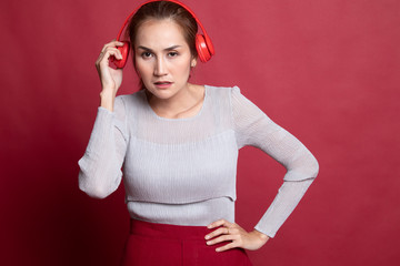 Too loud.  portrait of  young asian woman  holding  headphones and making unhappy face.