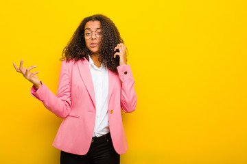 black business woman shrugging with a dumb, crazy, confused, puzzled expression, feeling annoyed...