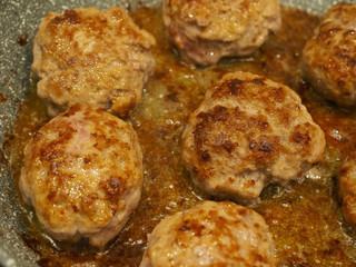 A closeup of patty-cakes roasted on a frying pan with oil