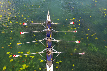 Men's quadruple rowing team on turquoise green lake