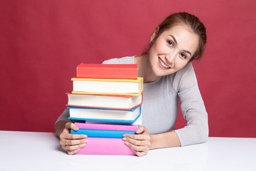 Happy young Asian woman read a book with books on table.