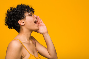 Young african american woman with skin birth mark shouting and holding palm near opened mouth.