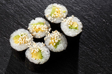 Maki Sushi Rolls with cucumber or avocado on black stone on dark background. Sushi menu. Japanese food. Closeup of delicious japanese food with sushi roll. Horizontal photo