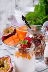 Natural yogurt, granola and mashed passion fruit and mango layered in a glass jar. Breakfast idea