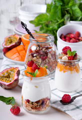 Natural yogurt, granola and mashed passion fruit and mango layered in a glass jar. Breakfast idea