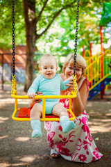 Loving mother hugs her little son in playground. Portrait of a beautiful mother with baby