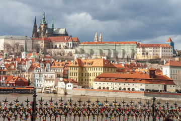 panoramic ancient cityscape Prague with Vltava river and famous Castle and love locks fence overcast background, Czech Republic