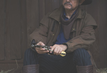 cowboy.cowboy sitting on the floor with hands holding a gun.