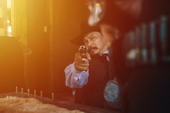 cowboy.cowboy sitting on the floor with hands holding a gun.