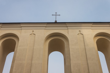 Obraz premium Bell tower with arches and cross of catholic church on blue sky background