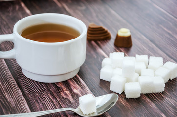 cup of tea, sugar cubes and a spoon on a wooden table. Close-up.