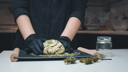The young female chef preparing to cooking hemp cake or bread. Close-up of fresh dough with...