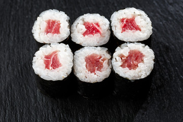 Maki Sushi Rolls with tuna on black stone on dark background. Sushi menu. Japanese food. Closeup of delicious japanese food with sushi roll. Horizontal photo