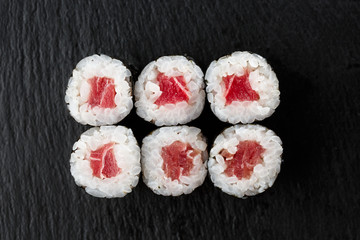 Maki Sushi Rolls with tuna on black stone on dark background. Sushi menu. Japanese food. Closeup of delicious japanese food with sushi roll. Horizontal photo