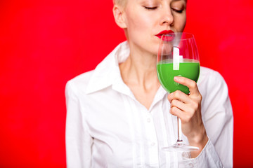 Girl hold green celery juice in glass over red background